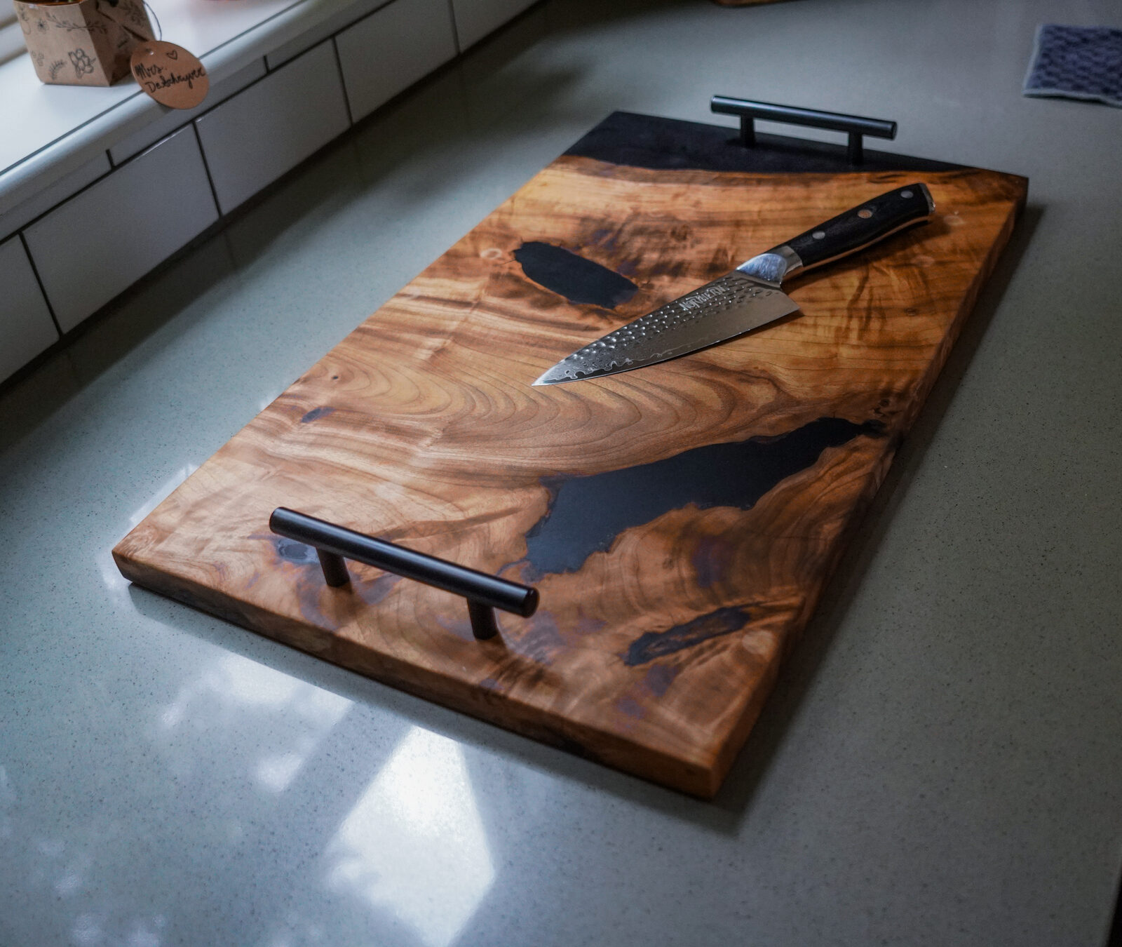 Live-edge walnut serving board with black epoxy river inlay and matching chef's knife