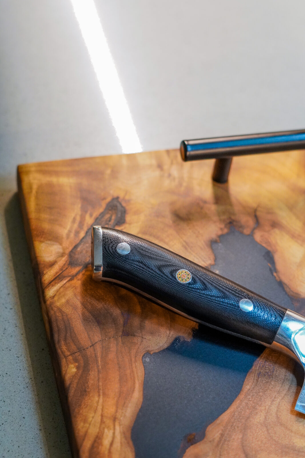 Detail of black epoxy river and handle on a live-edge walnut board